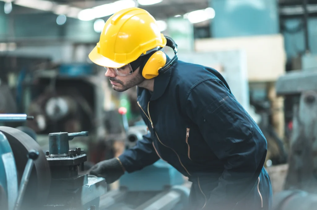 Industrial engineers in hard hats and working with heavy industrial machinery.