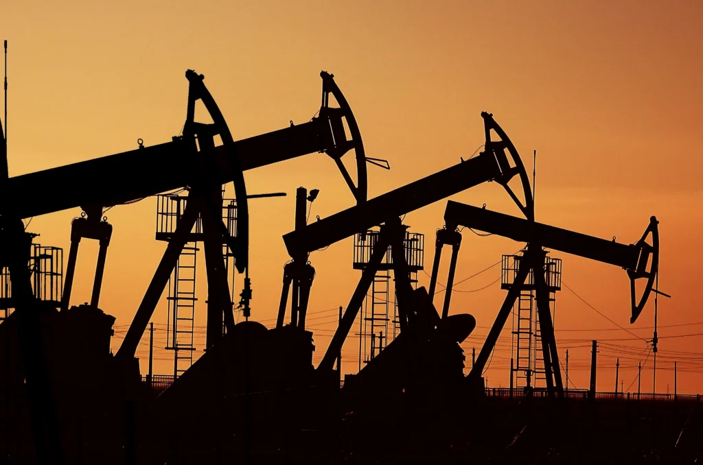 mage of oil pumps at sunset under the red sky on industrial platform field with crude petroleum hydraulic extraction units.